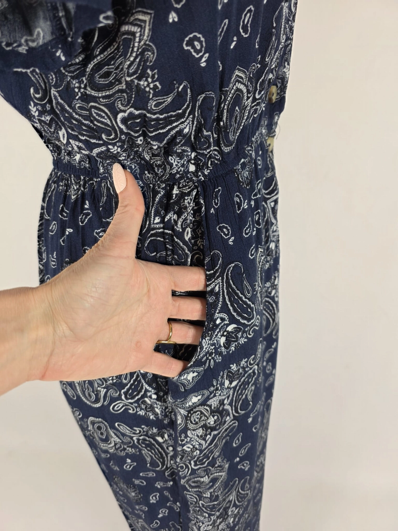 Damski kombinezon Ckh w kolorze granatowym z modnym wzorem paisley, zapinany na guziki, z gumką w pasie i praktycznymi kieszeniami.