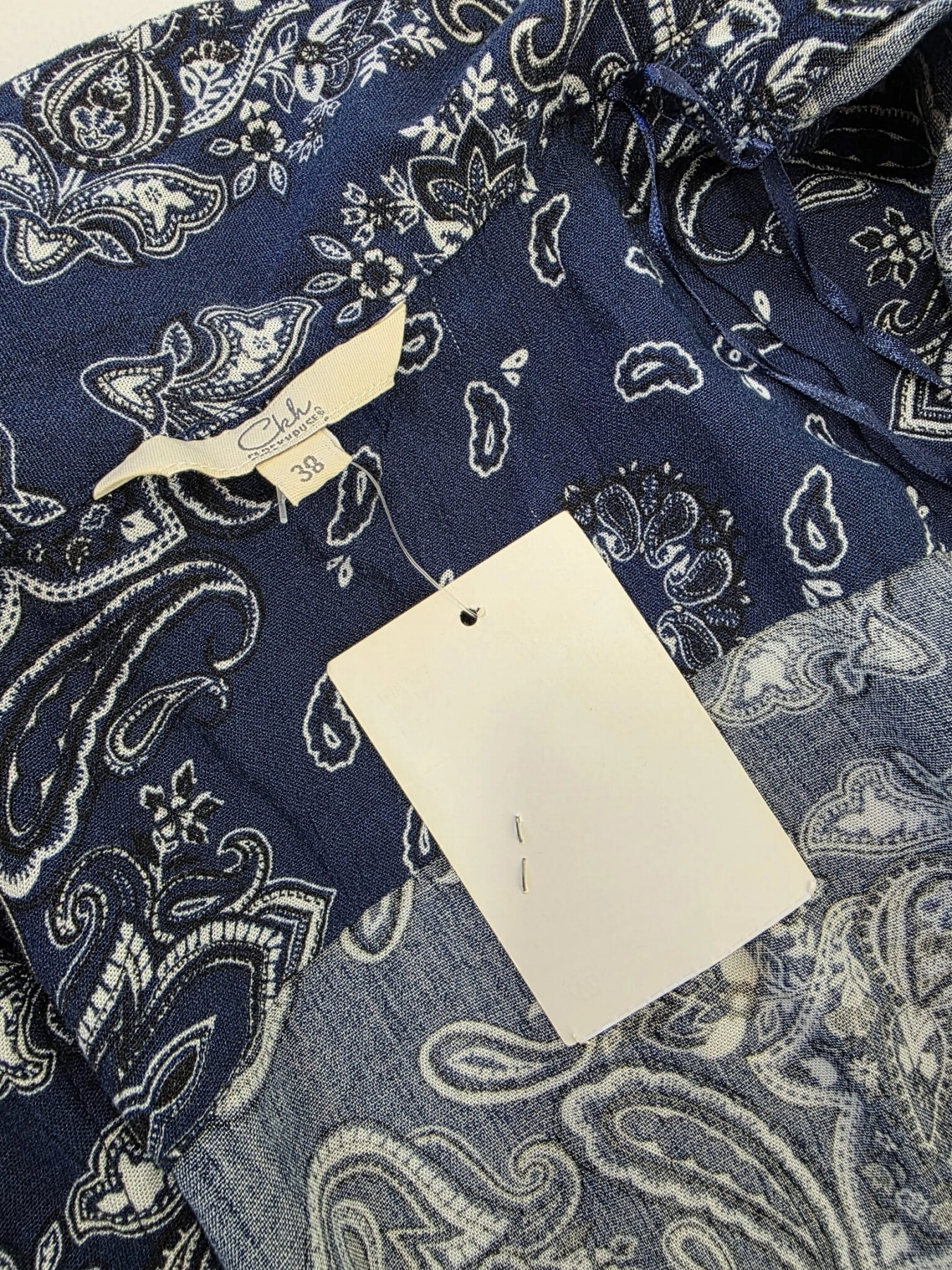 Damski kombinezon Ckh w kolorze granatowym z modnym wzorem paisley, zapinany na guziki, z gumką w pasie i praktycznymi kieszeniami.