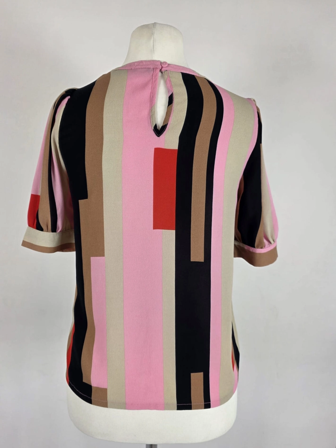 Oryginalna bluzka Vero Moda w różowo-brązowe geometryczne wzory, rozmiar XS, idealna do eleganckich i casualowych stylizacji.