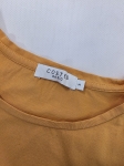Modna stylizacja warstwowa: kremowy ażurowy sweter Vero Moda, pomarańczowy t-shirt z falbankami Costes oraz czarna sukienka jeansowa Only