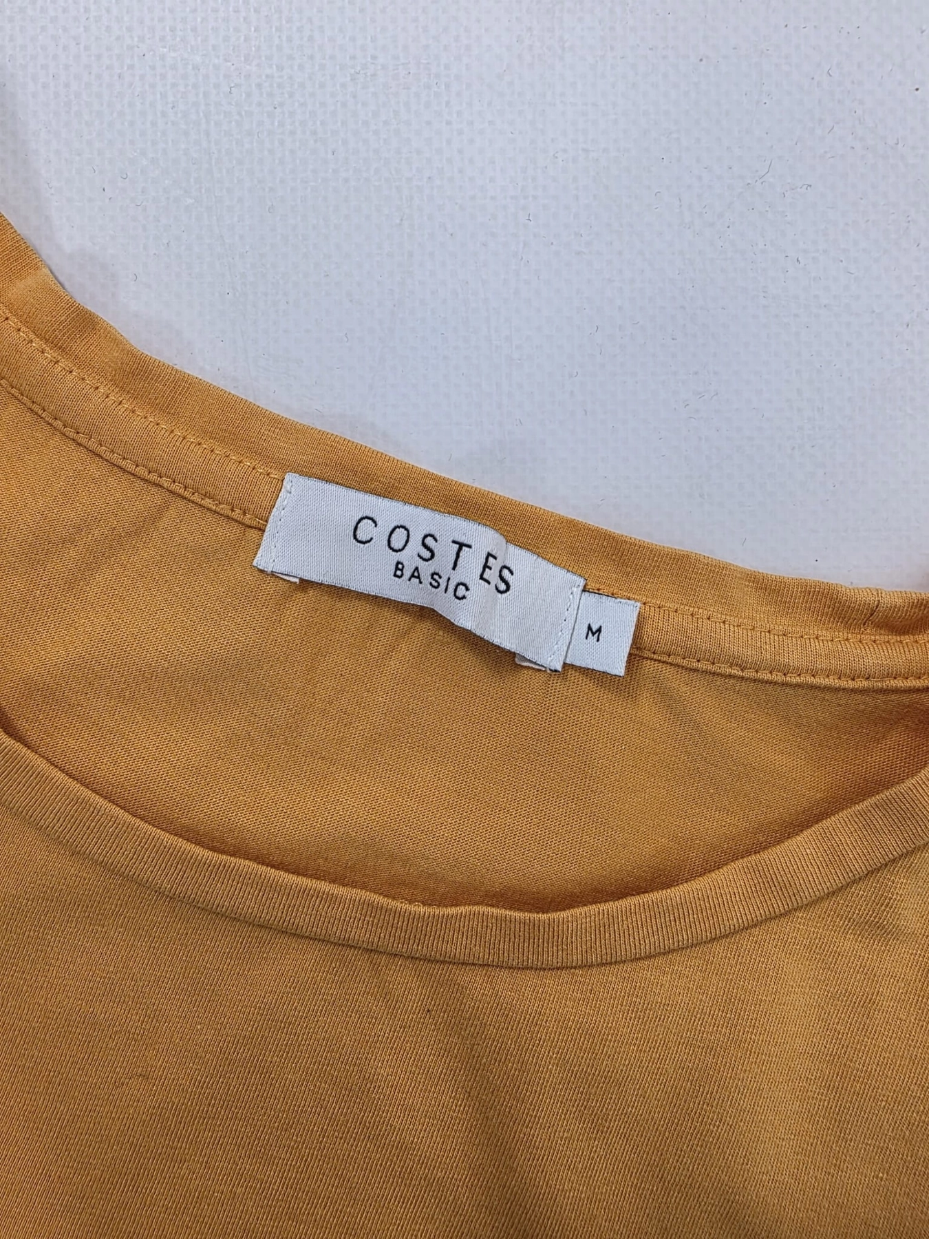 Modna stylizacja warstwowa: kremowy ażurowy sweter Vero Moda, pomarańczowy t-shirt z falbankami Costes oraz czarna sukienka jeansowa Only