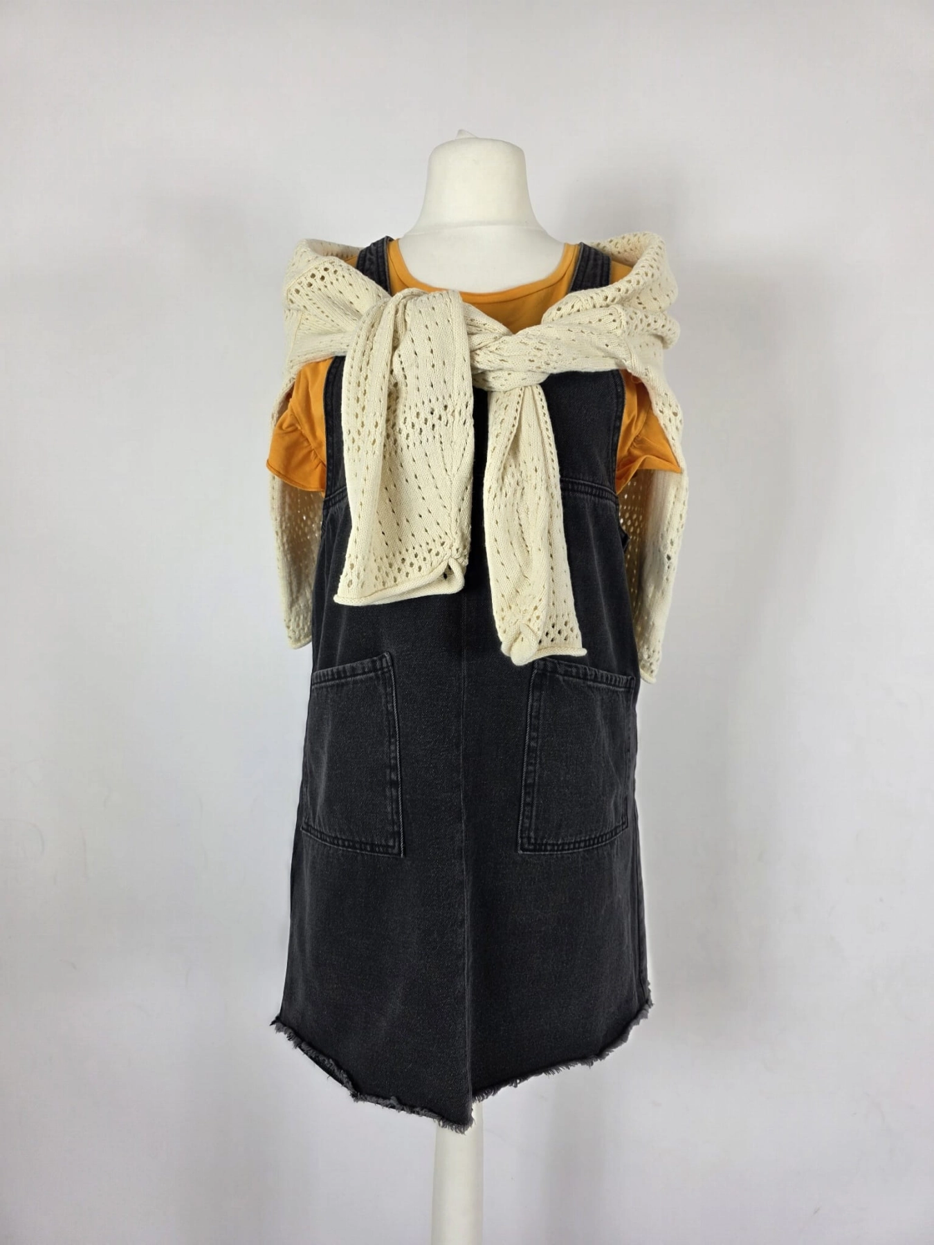 Modna stylizacja warstwowa: kremowy ażurowy sweter Vero Moda, pomarańczowy t-shirt z falbankami Costes oraz czarna sukienka jeansowa Only