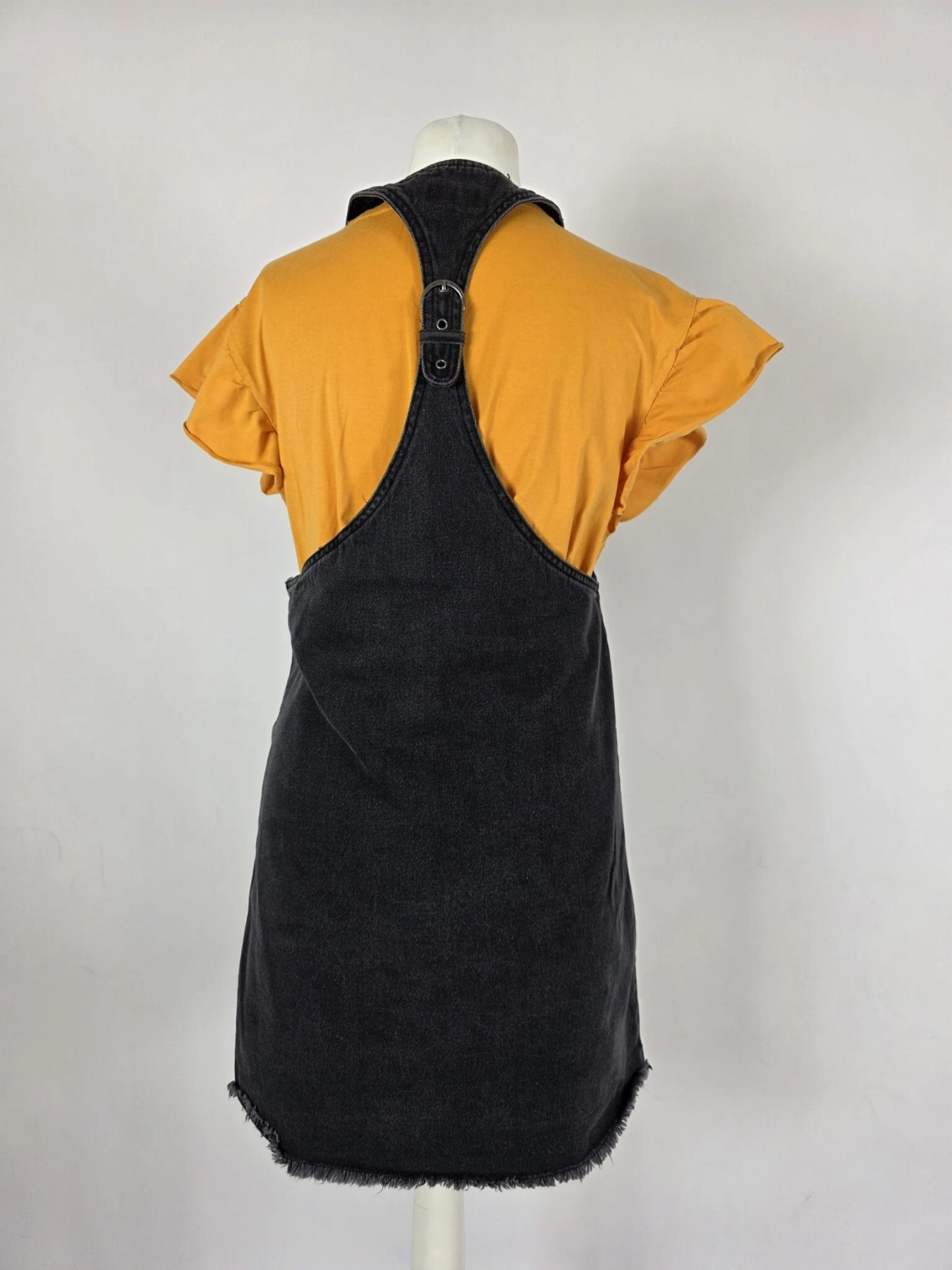 Modna stylizacja warstwowa: kremowy ażurowy sweter Vero Moda, pomarańczowy t-shirt z falbankami Costes oraz czarna sukienka jeansowa Only