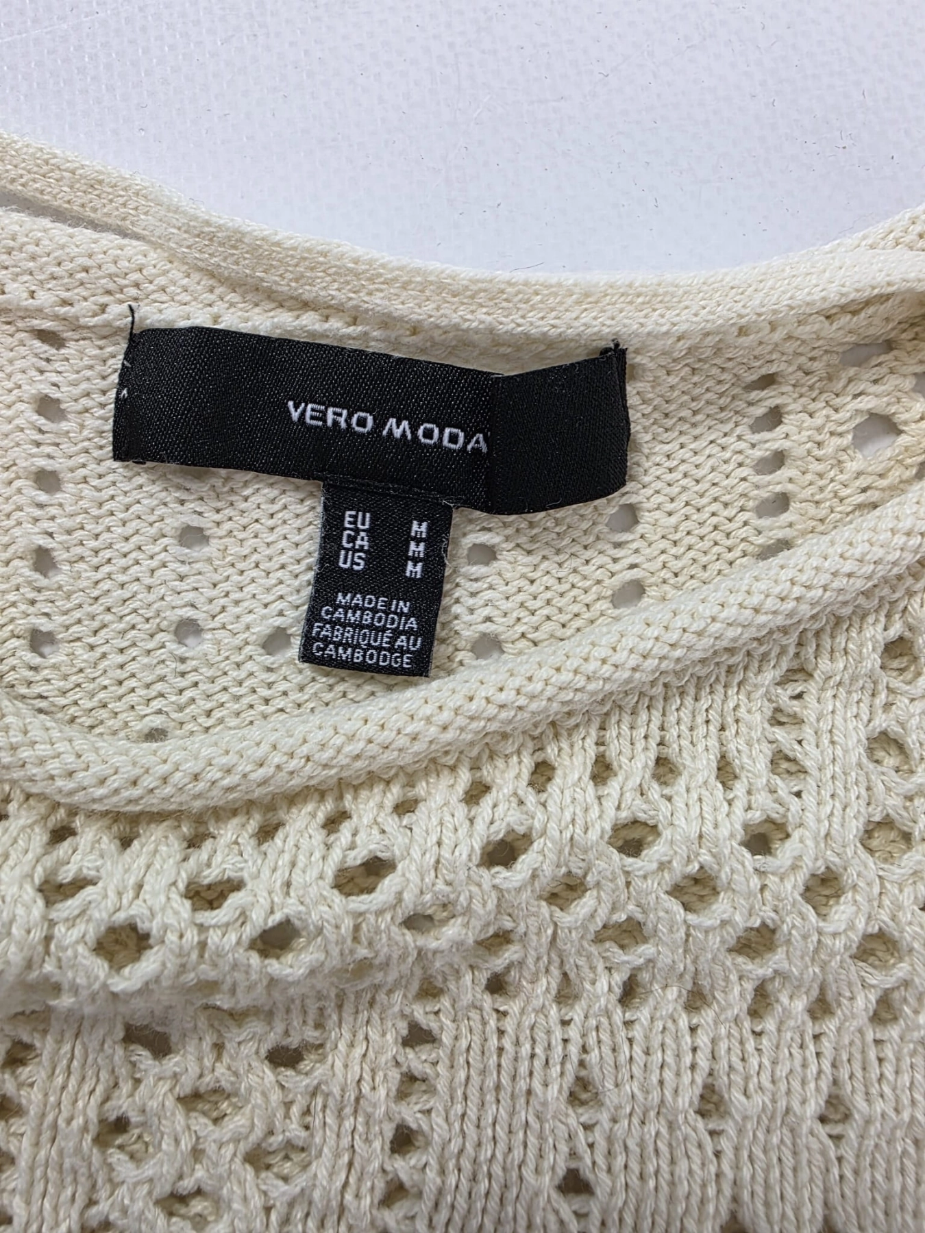 Modna stylizacja warstwowa: kremowy ażurowy sweter Vero Moda, pomarańczowy t-shirt z falbankami Costes oraz czarna sukienka jeansowa Only
