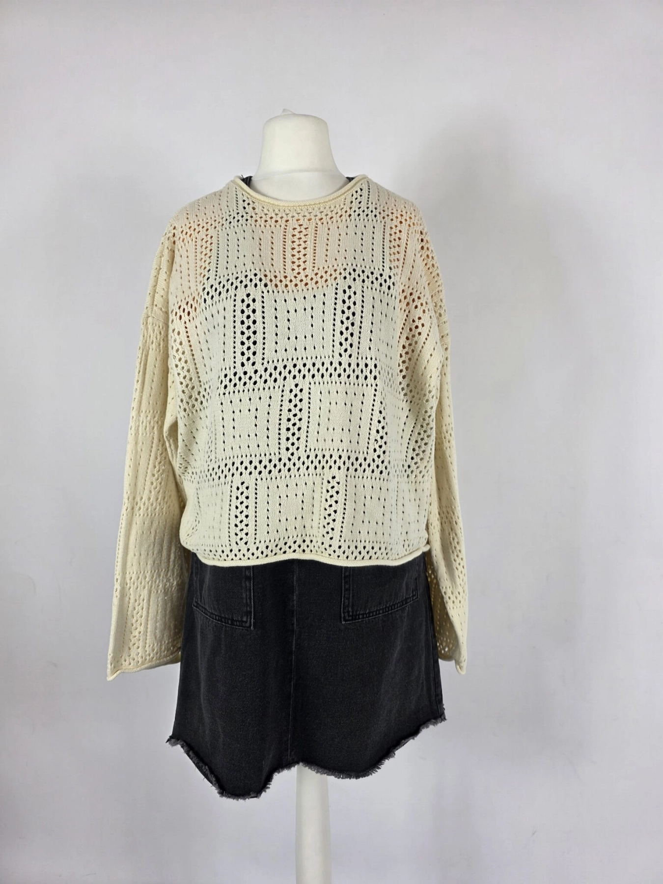 Modna stylizacja warstwowa: kremowy ażurowy sweter Vero Moda, pomarańczowy t-shirt z falbankami Costes oraz czarna sukienka jeansowa Only