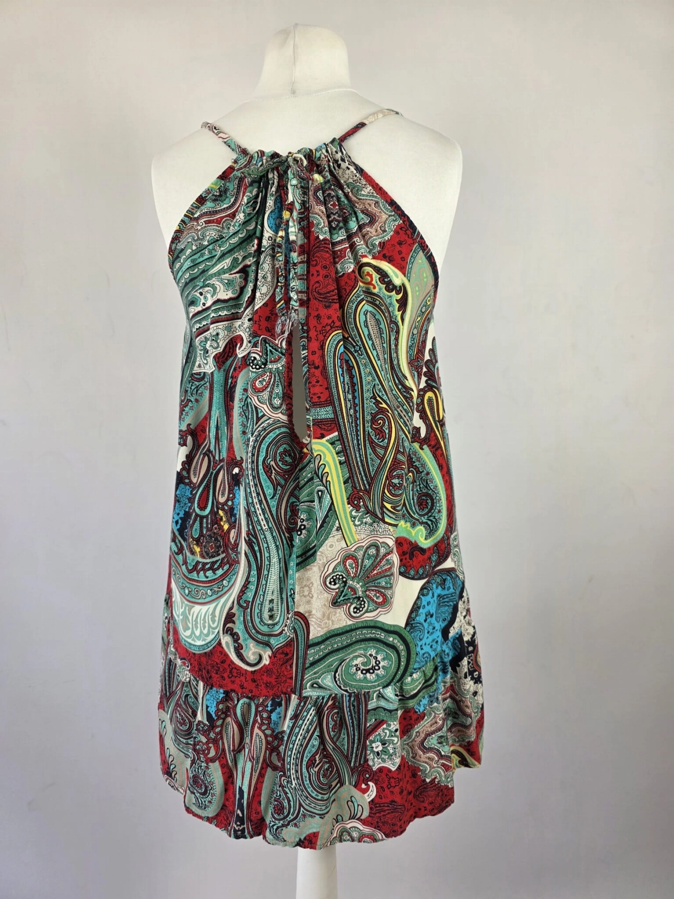 Kolorowa sukienka damska mini w orientalny wzór paisley, z wiązanym dekoltem typu halter i odkrytymi plecami, idealna na lato w stylu boho premium