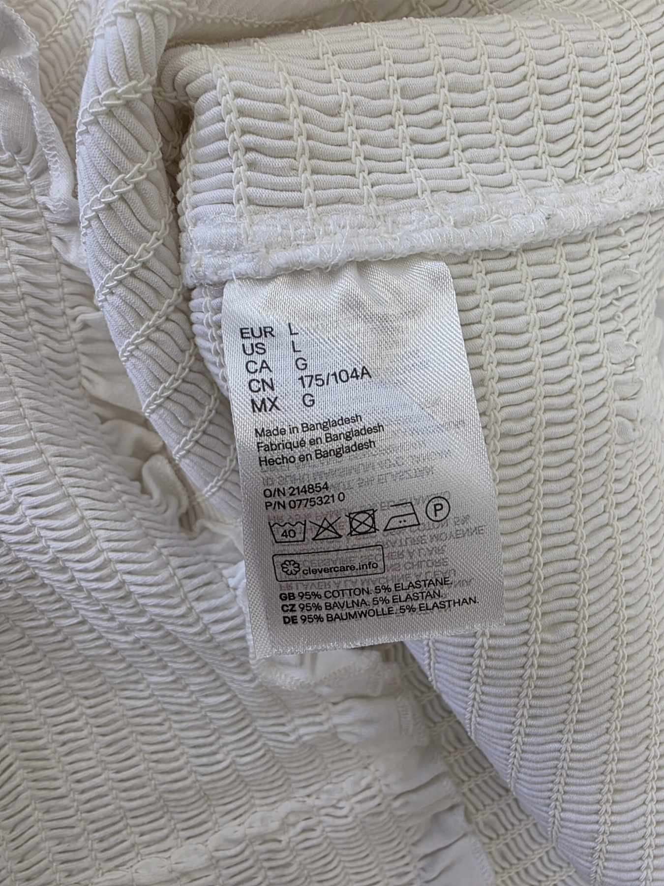 Trzyczęściowa stylizacja damska składająca się z białej ażurowej koszuli JDY, marszczonego topu gorsetowego H&amp;M oraz beżowych spodni z wysokim stanem