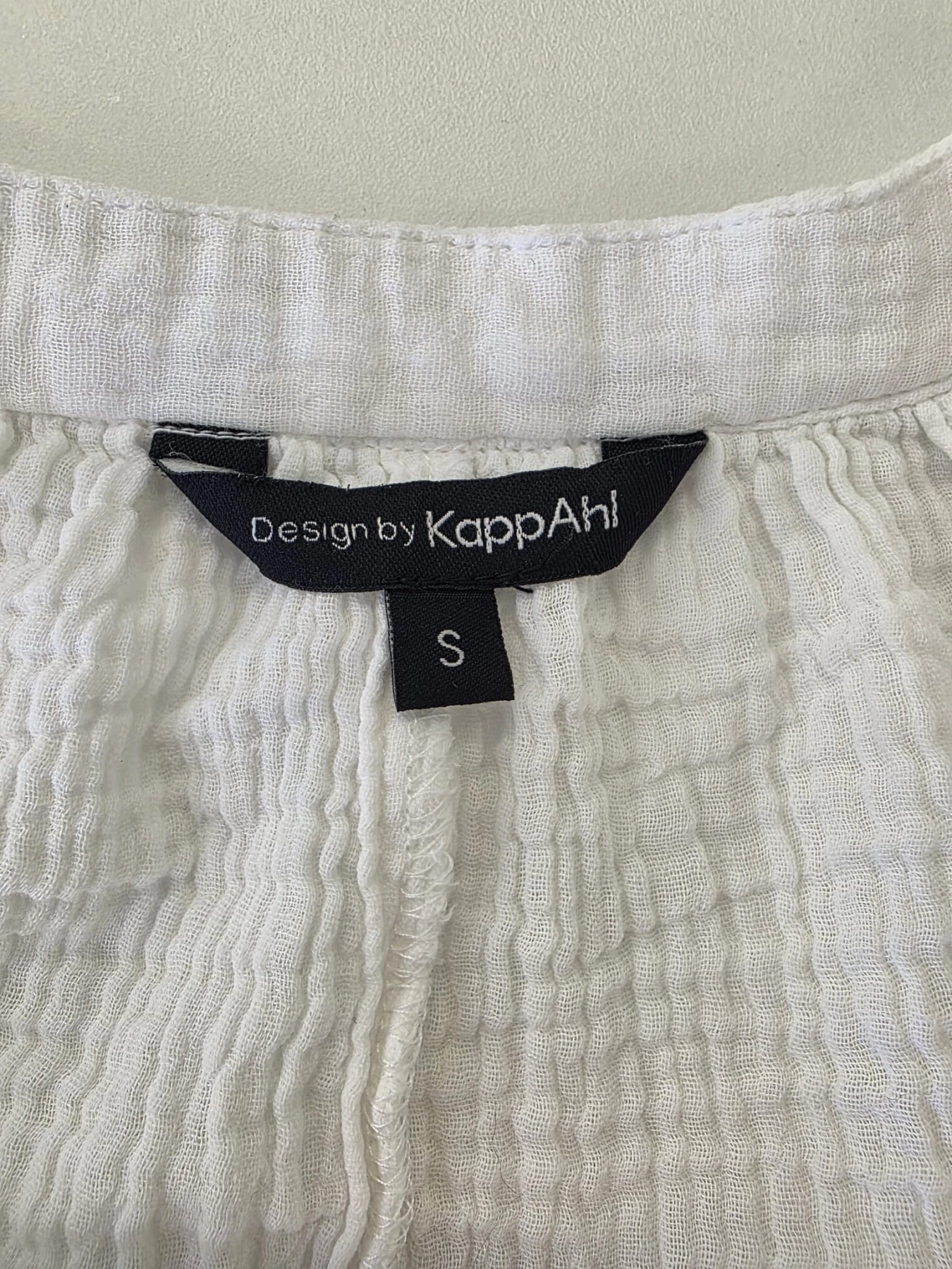 Długa biała tunika koszulowa Design by KappAhl wykonana w 100% z miękkiej bawełny o strukturyzowanej fakturze, idealna jako lekka narzutka plażowa lub stylowa, codzienna sukienka