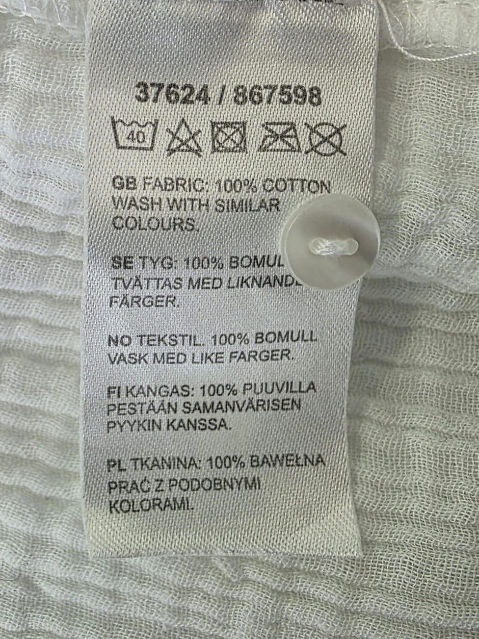 Długa biała tunika koszulowa Design by KappAhl wykonana w 100% z miękkiej bawełny o strukturyzowanej fakturze, idealna jako lekka narzutka plażowa lub stylowa, codzienna sukienka