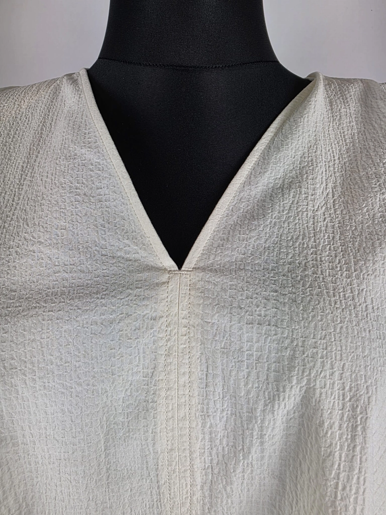 Kremowa sukienka oversize marki COS o gofrowanej strukturze, z dekoltem w serek i wiązaniem na plecach, idealna do minimalistycznych, letnich stylizacji premium