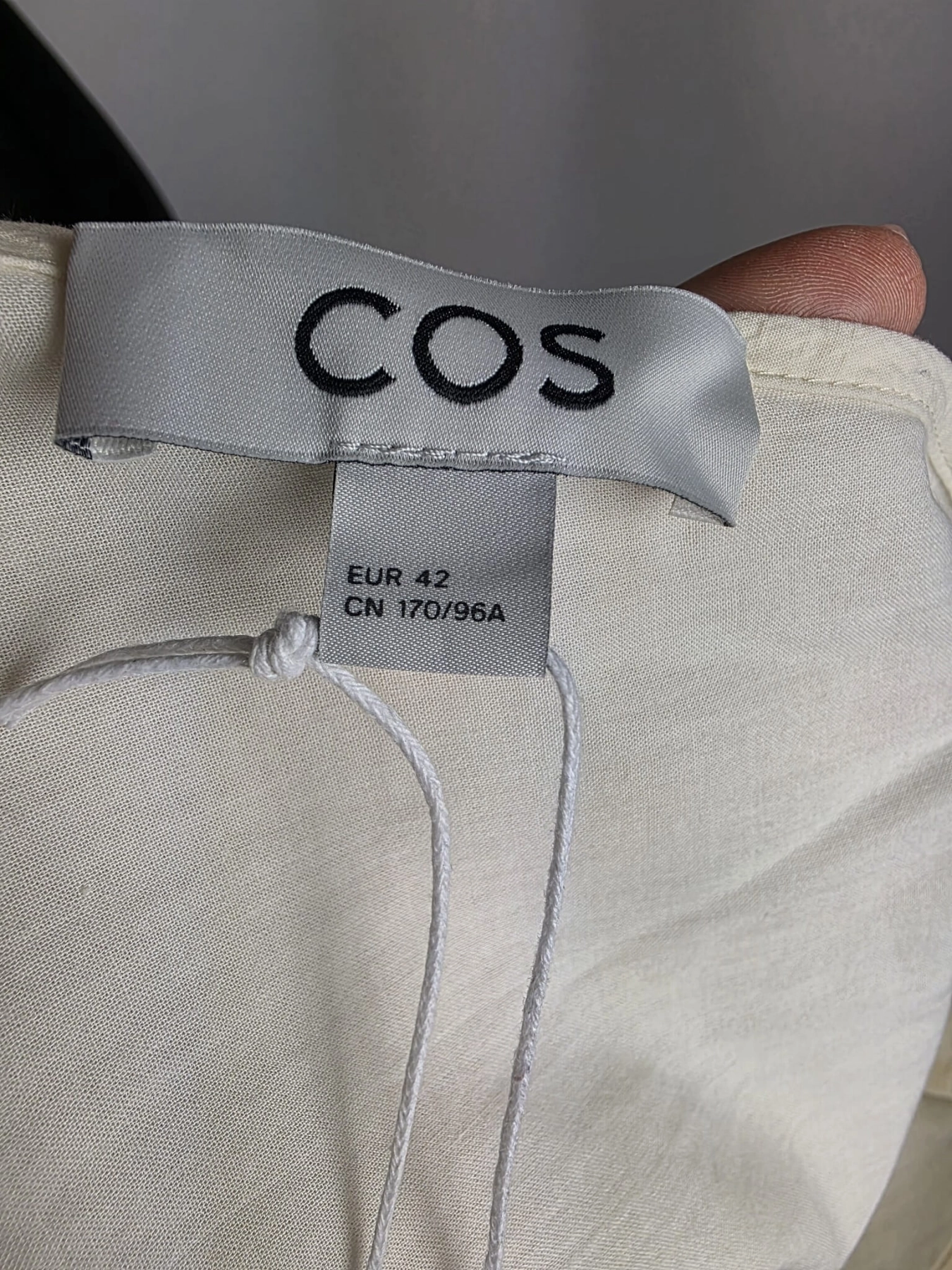 Kremowa sukienka oversize marki COS o gofrowanej strukturze, z dekoltem w serek i wiązaniem na plecach, idealna do minimalistycznych, letnich stylizacji premium