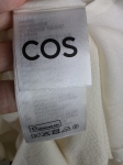 Kremowa sukienka oversize marki COS o gofrowanej strukturze, z dekoltem w serek i wiązaniem na plecach, idealna do minimalistycznych, letnich stylizacji premium