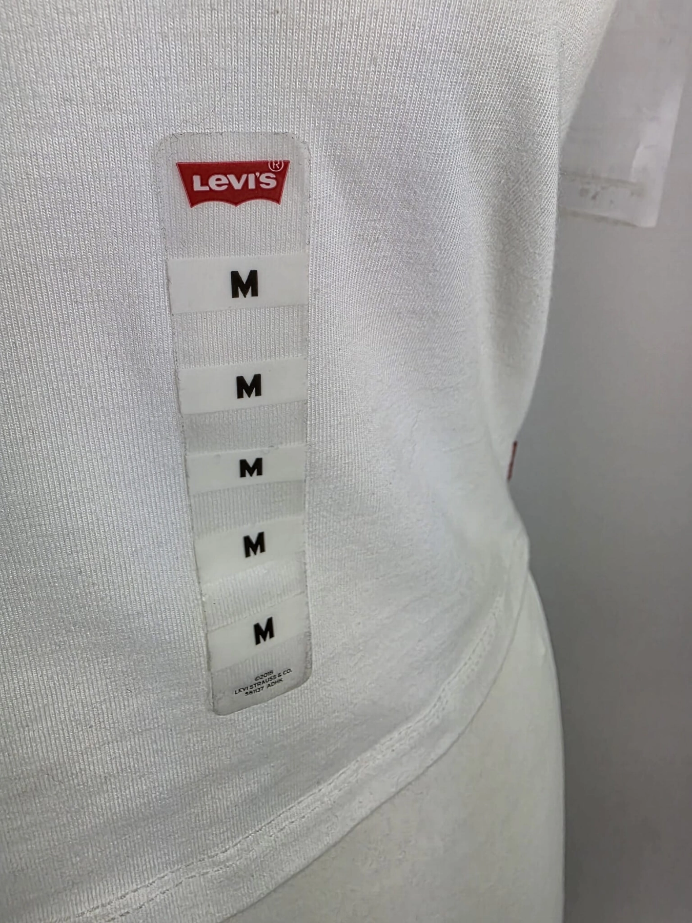 Oryginalny asymetryczny top damski Levi's w rozmiarze M, wykonany z prążkowanej bawełny w kolorze białym z subtelnym logo na piersi