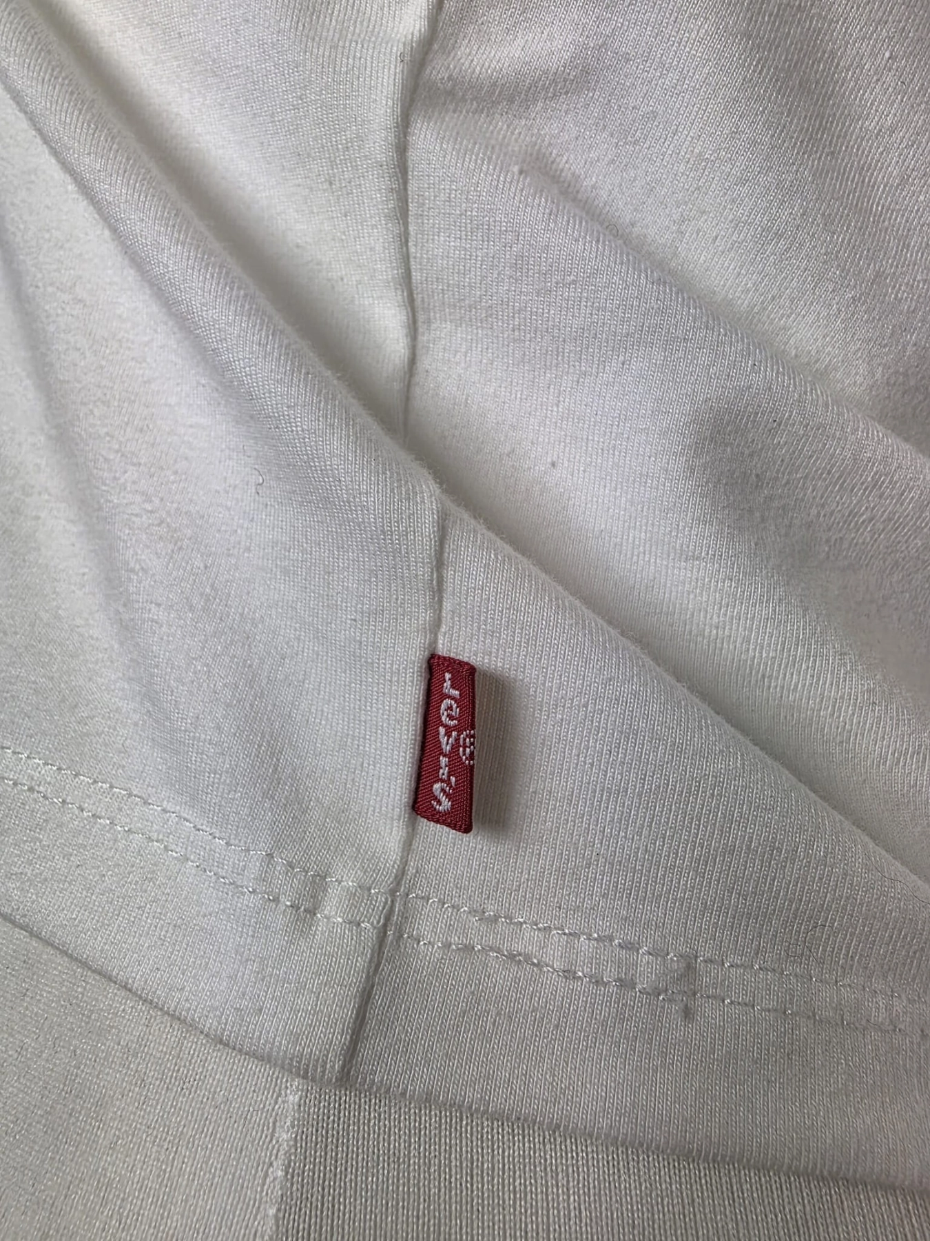 Oryginalny asymetryczny top damski Levi's w rozmiarze M, wykonany z prążkowanej bawełny w kolorze białym z subtelnym logo na piersi