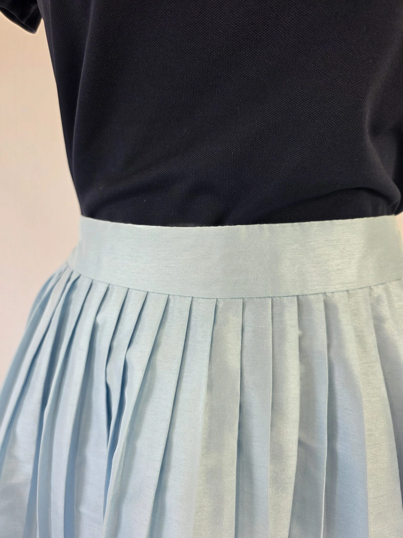 Ekskluzywny komplet premium składający się z granatowego polo Helly Hansen i błękitnej, plisowanej spódnicy midi marki COS to idealna, kobieca stylizacja na każdą okazję
