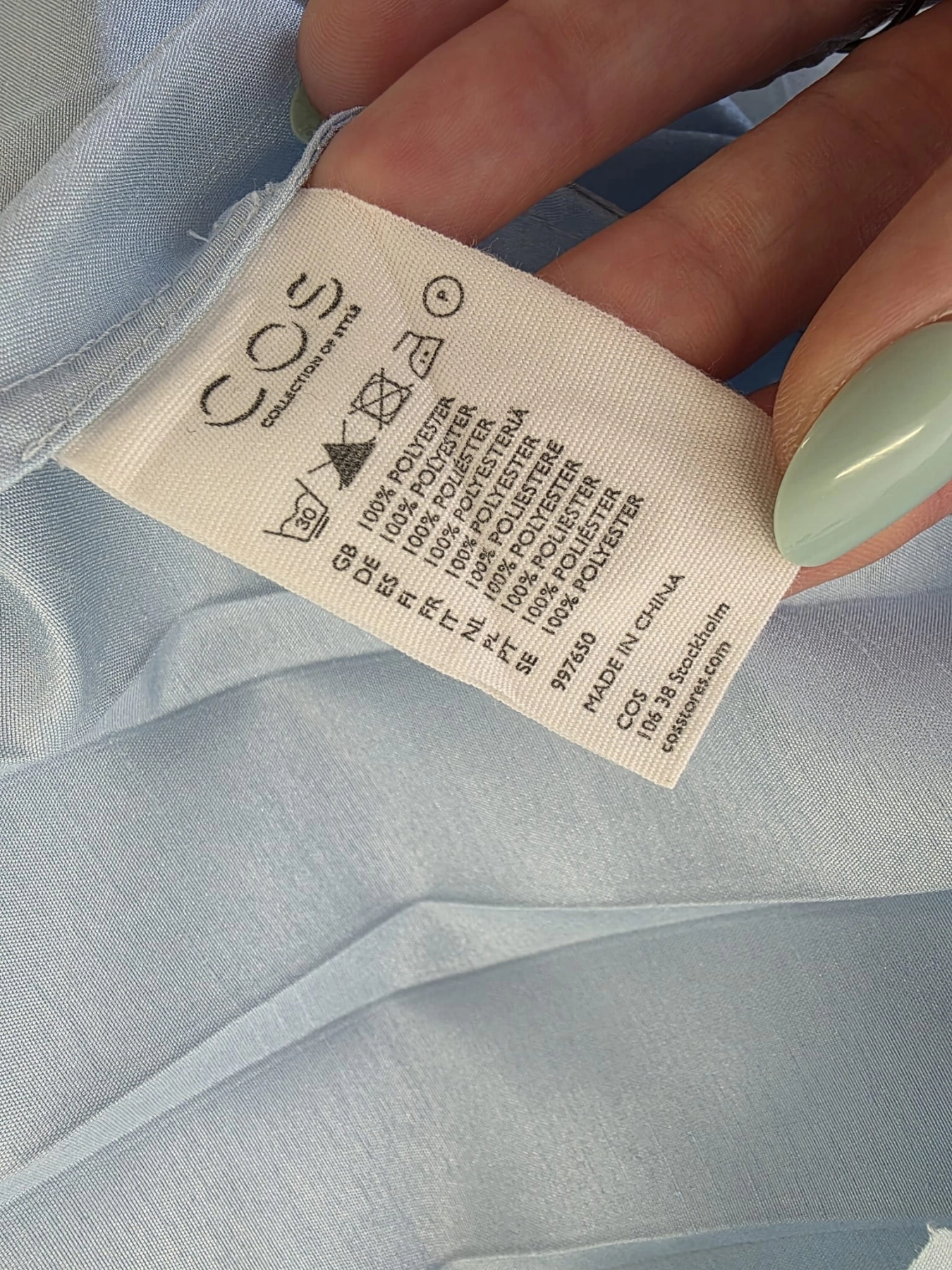 Ekskluzywny komplet premium składający się z granatowego polo Helly Hansen i błękitnej, plisowanej spódnicy midi marki COS to idealna, kobieca stylizacja na każdą okazję