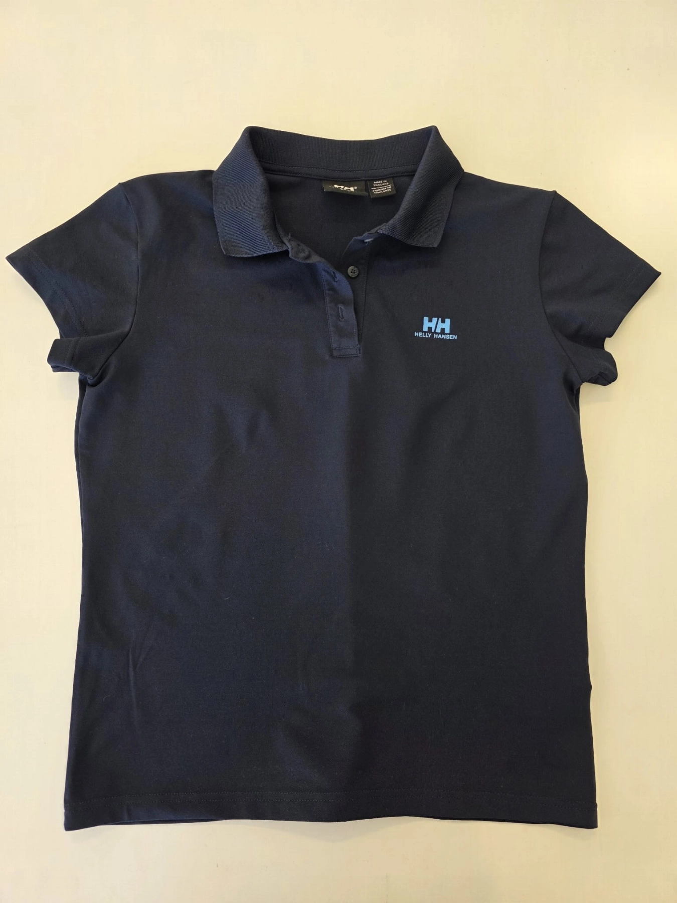 Ekskluzywny komplet premium składający się z granatowego polo Helly Hansen i błękitnej, plisowanej spódnicy midi marki COS to idealna, kobieca stylizacja na każdą okazję