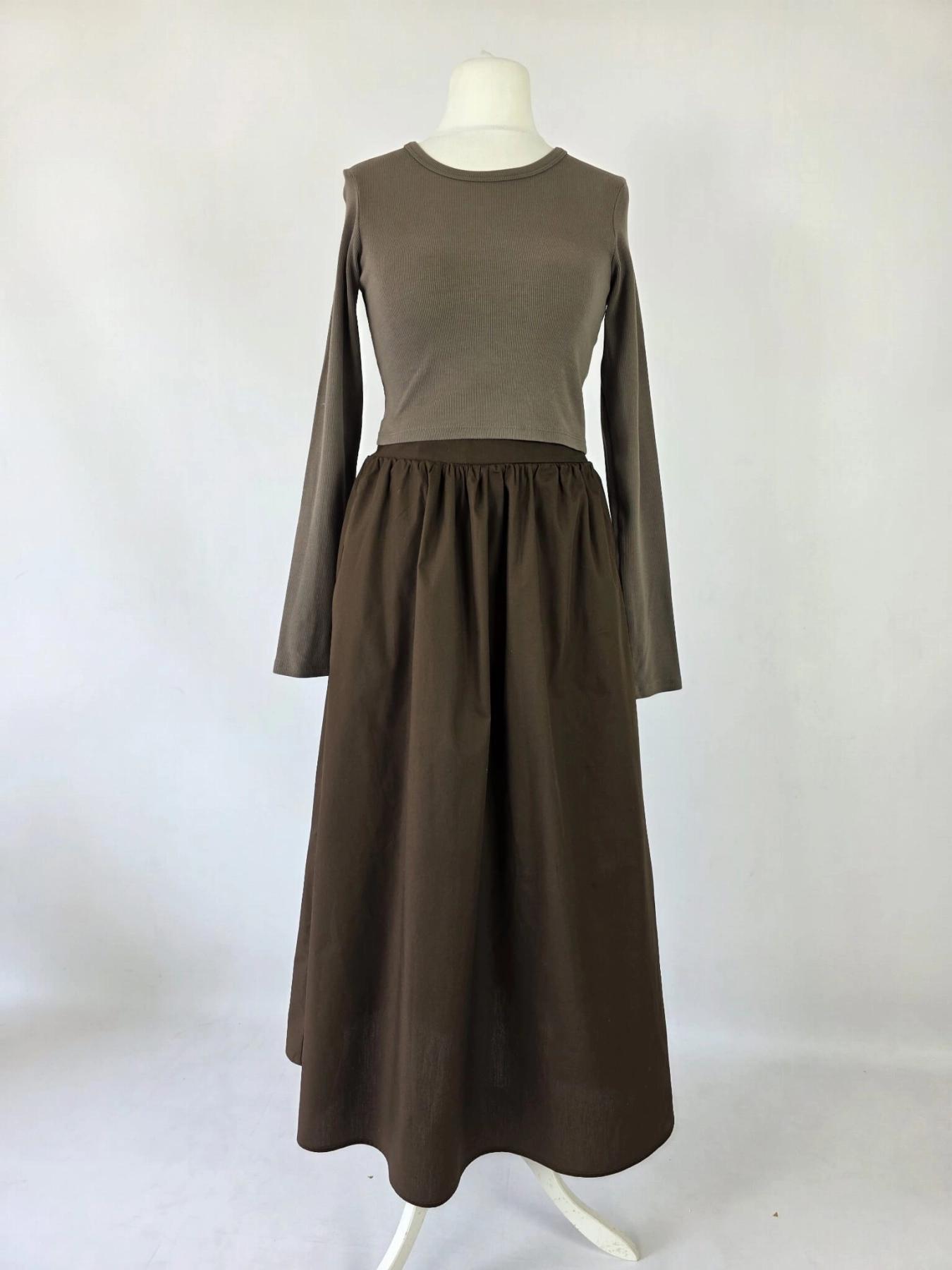 Czekoladowa stylizacja damska z dopasowaną bluzką JJXX, bawełnianą spódnicą Threadbare oraz wełnianym narzutem fransa gwarantuje elegancki wygląd i pełen komfort noszenia