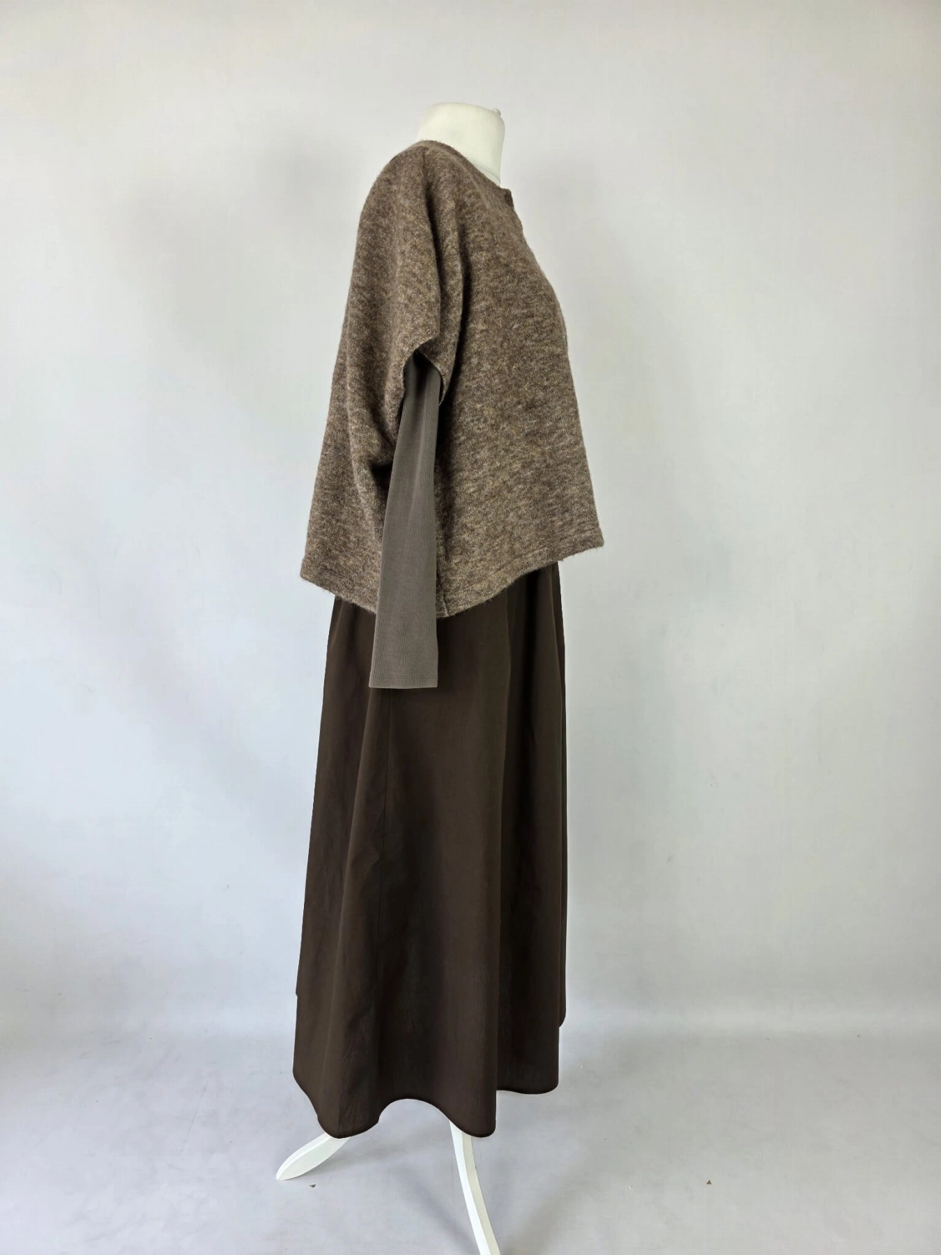 Czekoladowa stylizacja damska z dopasowaną bluzką JJXX, bawełnianą spódnicą Threadbare oraz wełnianym narzutem fransa gwarantuje elegancki wygląd i pełen komfort noszenia