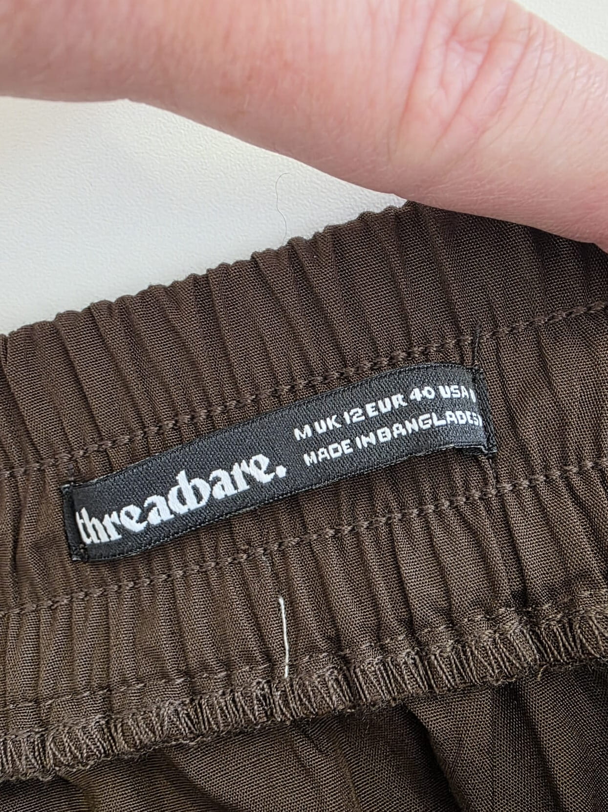 Czekoladowa stylizacja damska z dopasowaną bluzką JJXX, bawełnianą spódnicą Threadbare oraz wełnianym narzutem fransa gwarantuje elegancki wygląd i pełen komfort noszenia