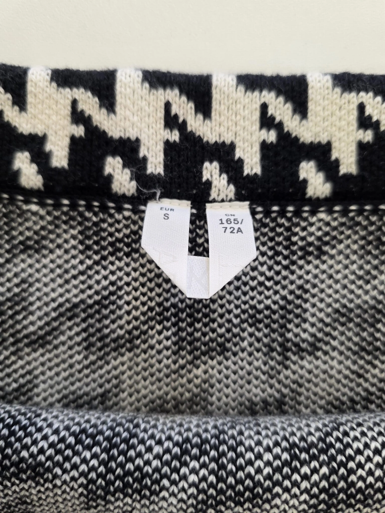 Stylizacja z czarną koszulą z falbaną Divided  i bawełnianą spódnicą mini w pepitkę od ARKET to elegancki zestaw damski podkreślający sylwetkę