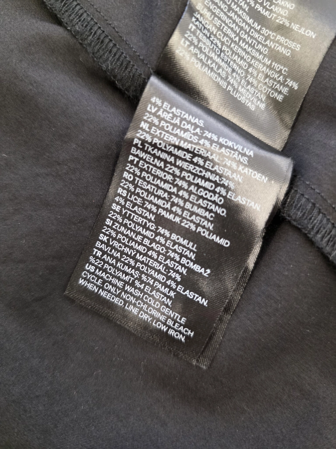 Stylizacja z czarną koszulą z falbaną Divided  i bawełnianą spódnicą mini w pepitkę od ARKET to elegancki zestaw damski podkreślający sylwetkę