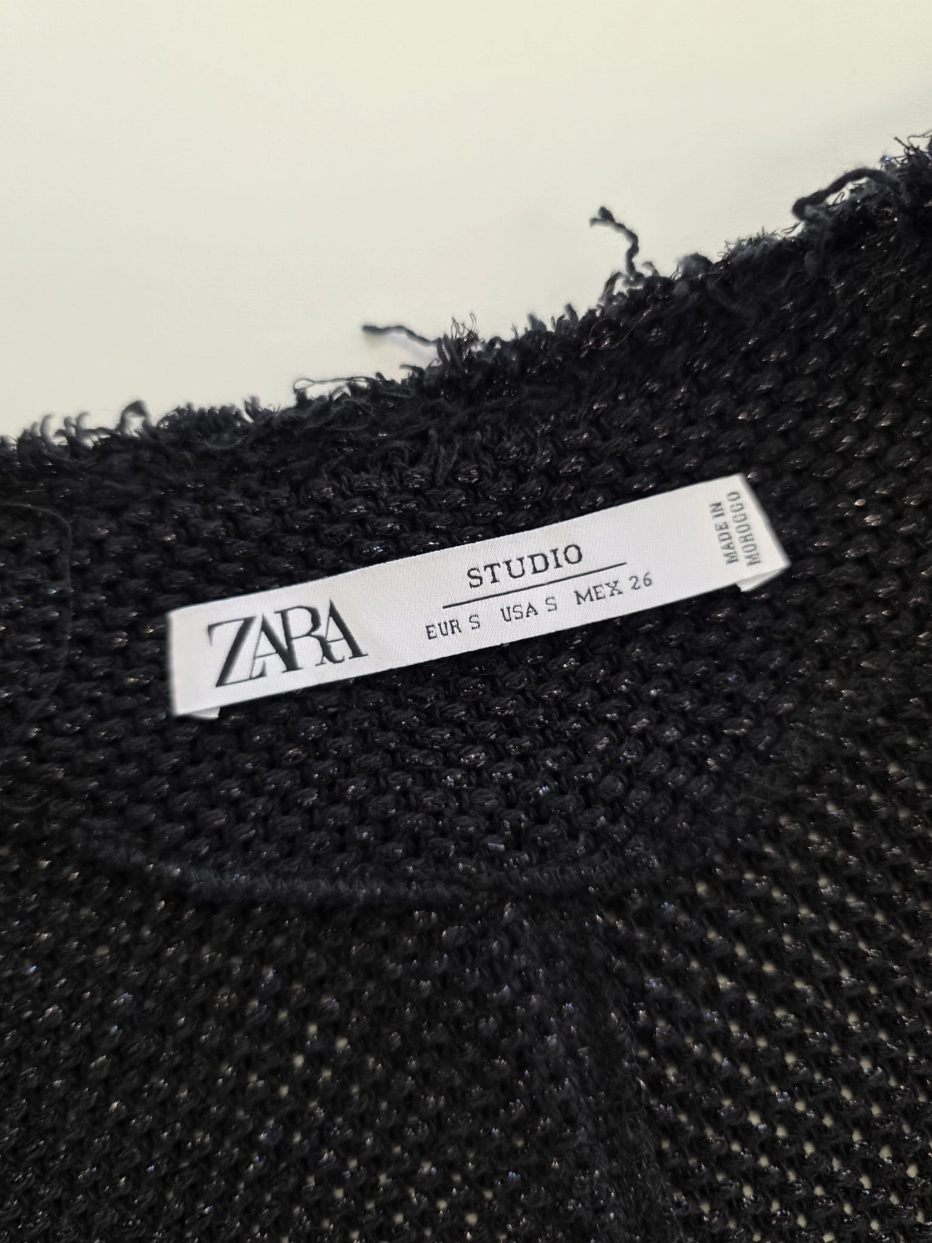 Czarny sweter damski ZARA Studio z asymetrycznymi frędzlami i błyszczącą nitką to stylowe ubranie idealne na wieczorowe wyjścia oraz eleganckie stylizacje