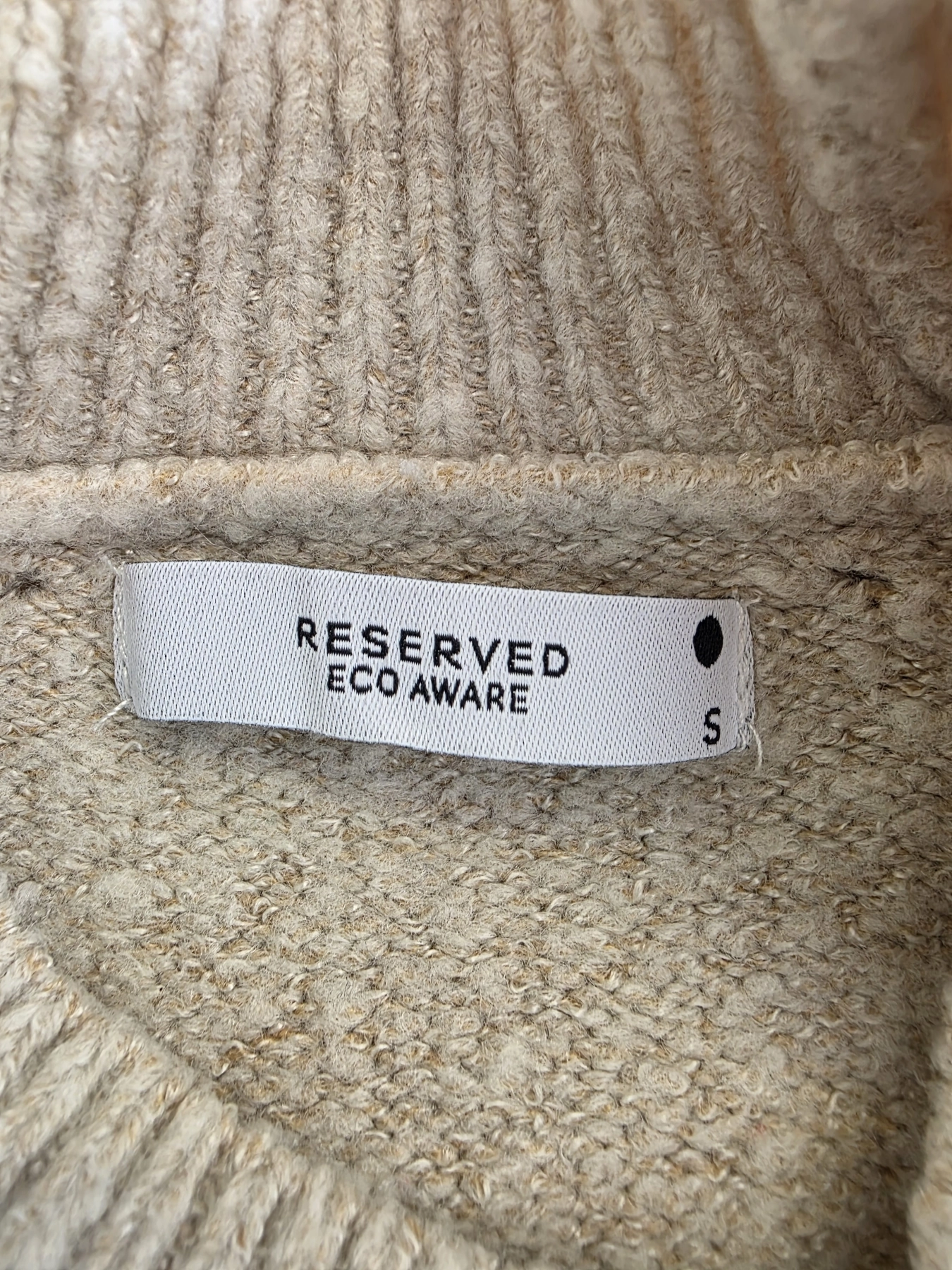 Kobieca, beżowa sukienka dzianinowa marki Reserved z plisowanym, zwiewnym dołem doskonale łączy komfort z eleganckim, nowoczesnym stylem