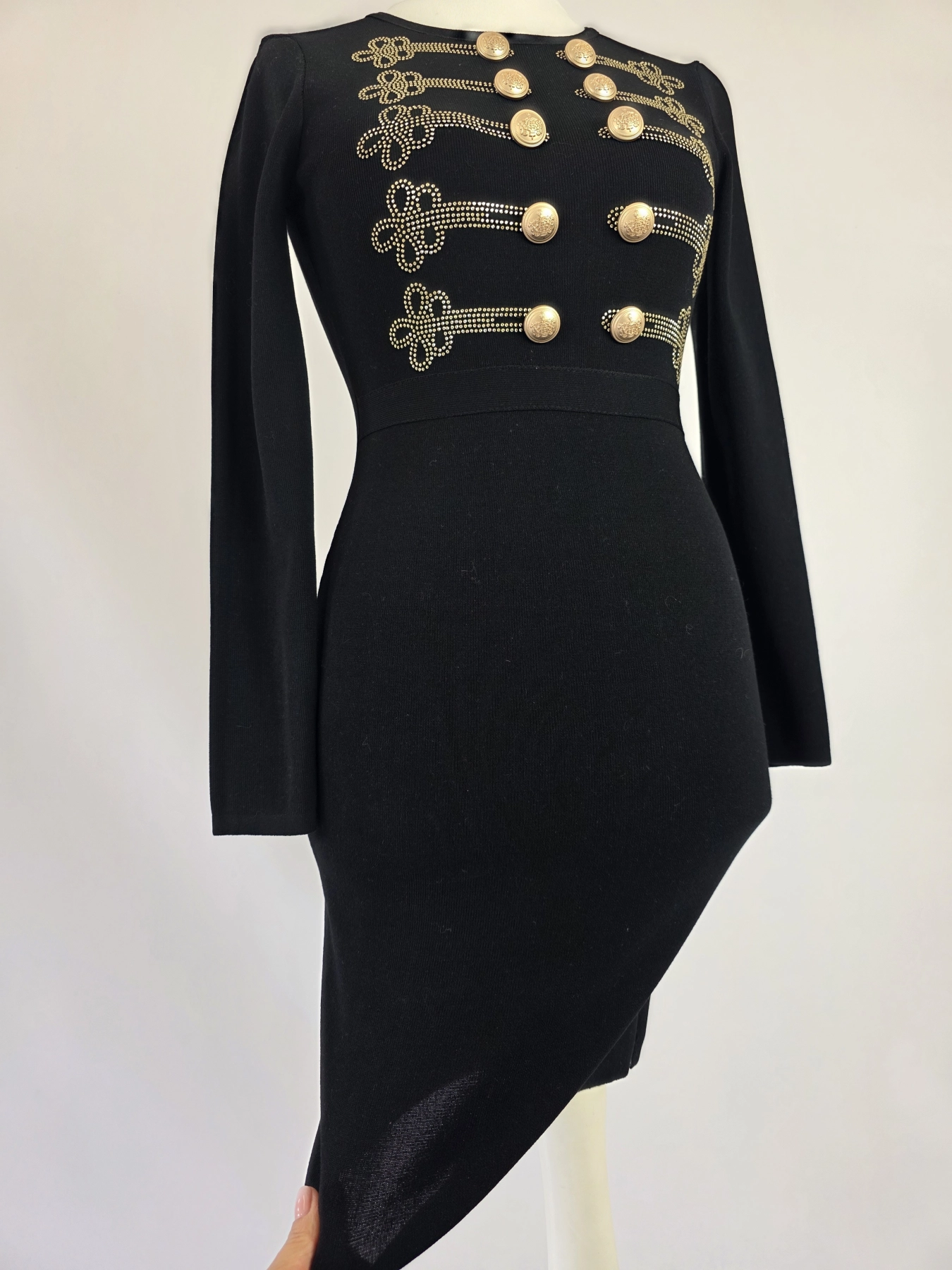 Elegancka czarna sukienka dresowa Allyson Collection ze złotymi guzikami i dżetami doskonale podkreśla kobiecą sylwetkę, łącząc styl militarny z wyjątkową wygodą