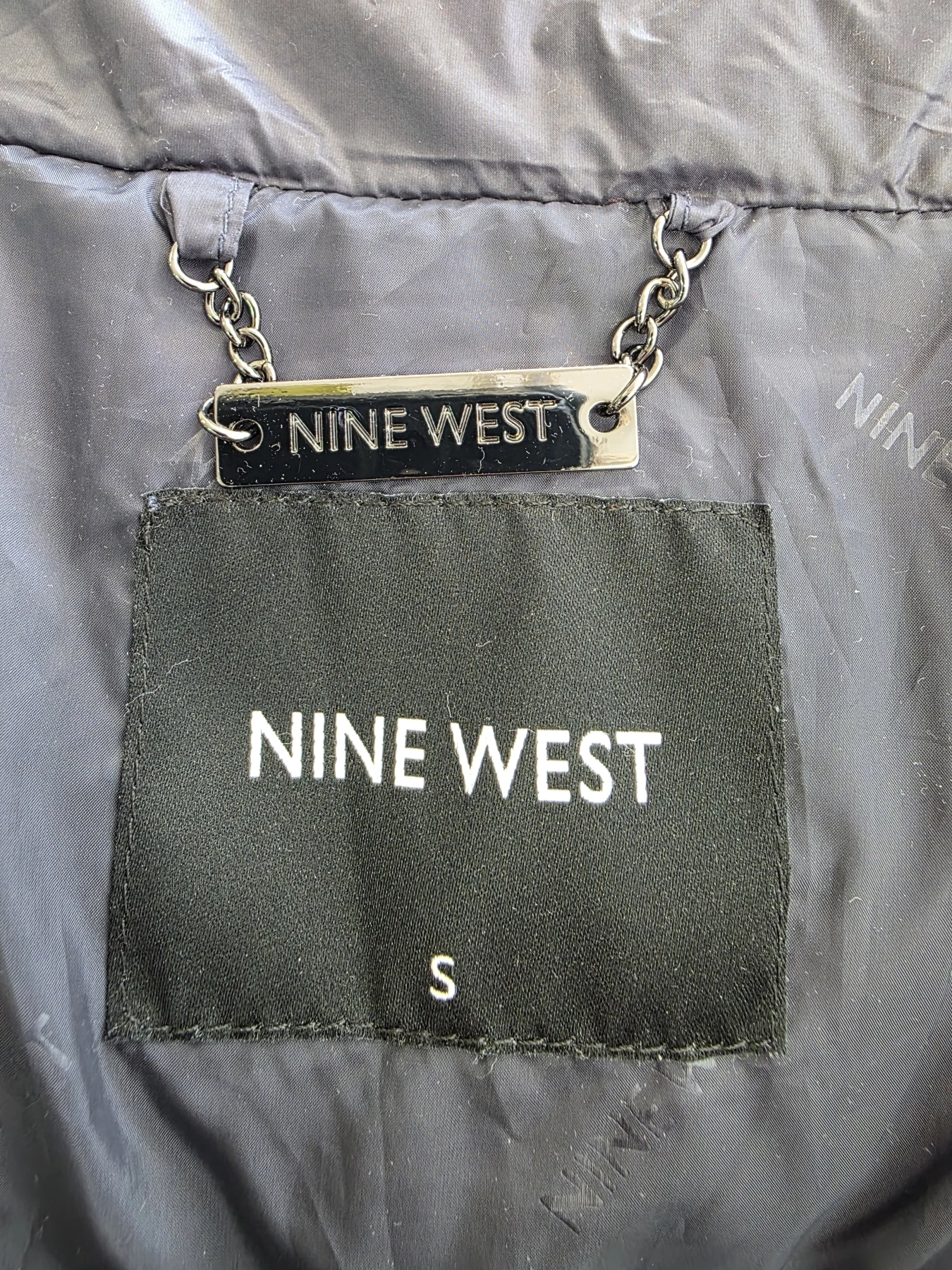 Odkryj elegancką, pikowaną kurtkę damską z kapturem Nine West w kolorze ciemnoszarym, która idealnie wysmukla sylwetkę i zapewnia ciepło