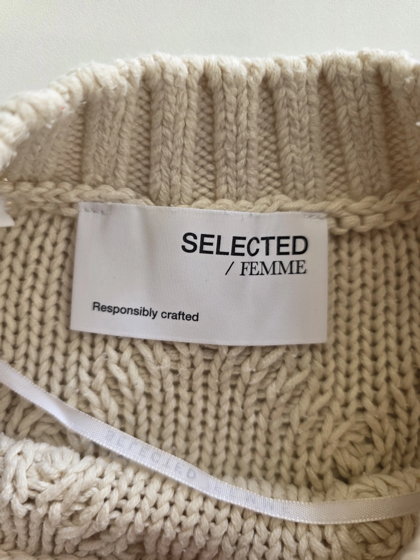 Damska stylizacja składająca się z kremowego bezrękawnika Selected / Femme o splotach warkoczowych oraz brązowo-szarych spodni z wysokim stanem to idealny zestaw premium łączący elegancję z codziennym komfortem
