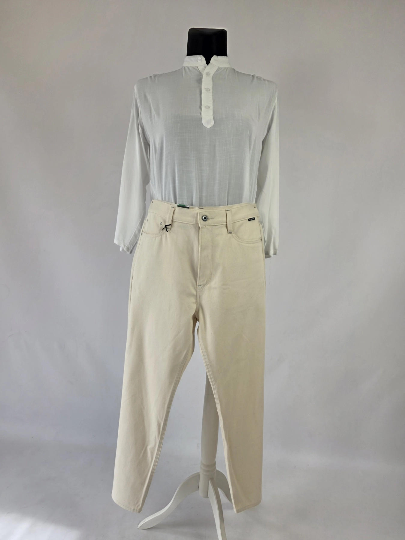 Stylowy komplet damski skomponowany przez stylistkę, składający się z długiego kardiganu Niumi, białej bluzki oraz jasnych spodni G-Star RAW z broszką