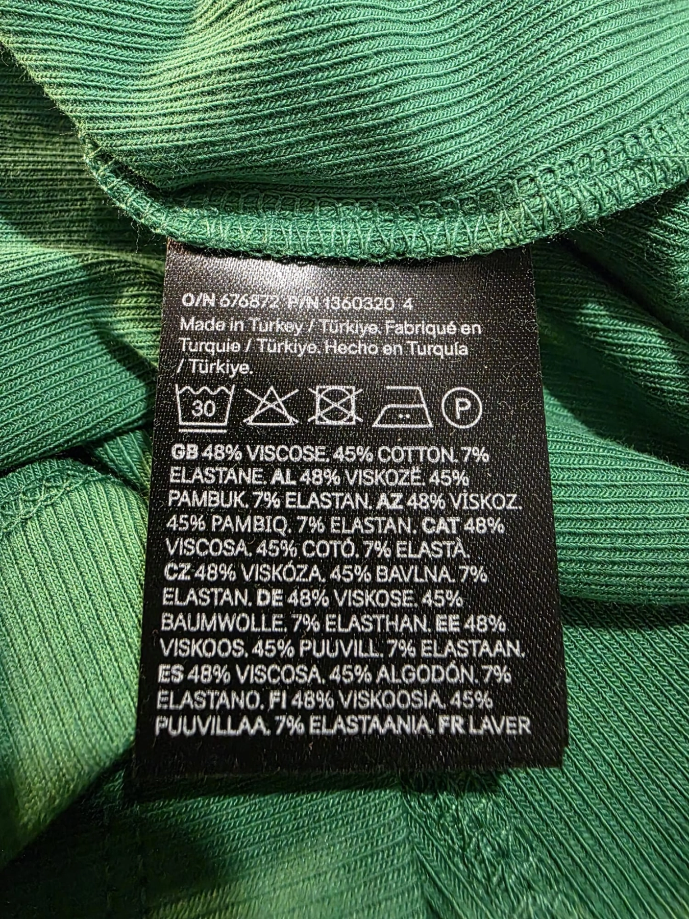 Damski komplet stylizowany przez stylistkę, składający się z zielonej bluzki z długim rękawem oraz kloszowanej spódnicy w geometryczne paski marki MAXandCo. z wygodnymi kieszeniami