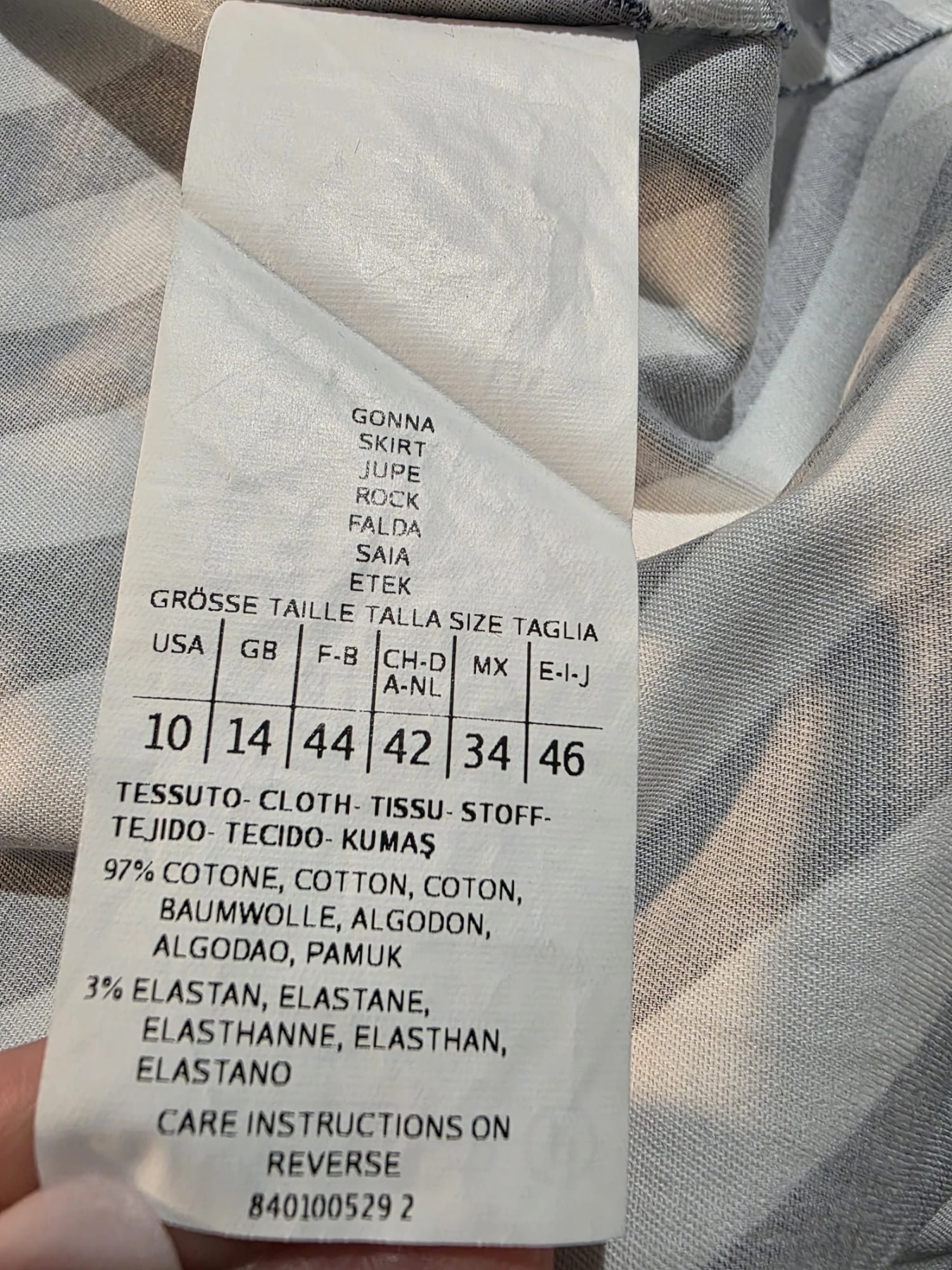 Damski komplet stylizowany przez stylistkę, składający się z zielonej bluzki z długim rękawem oraz kloszowanej spódnicy w geometryczne paski marki MAXandCo. z wygodnymi kieszeniami