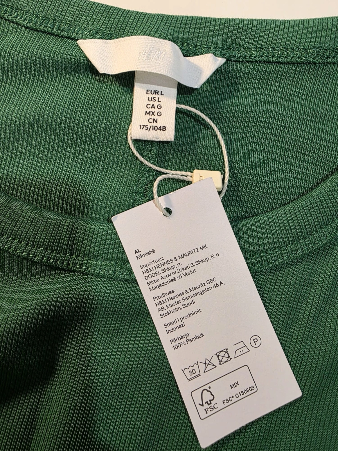 Damski komplet stylizowany przez stylistkę, składający się z zielonej bluzki z długim rękawem oraz kloszowanej spódnicy w geometryczne paski marki MAXandCo. z wygodnymi kieszeniami