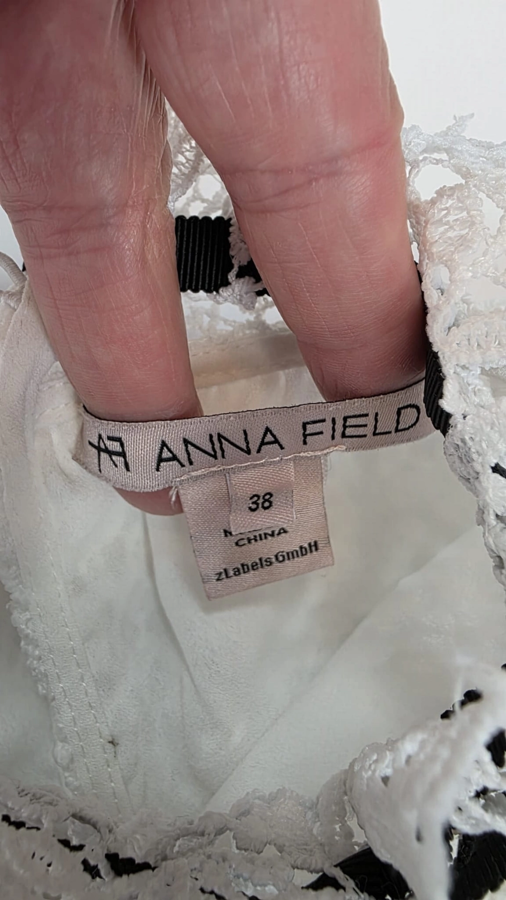 Biała koronkowa sukienka z czarną kokardą od ANNA FIELD